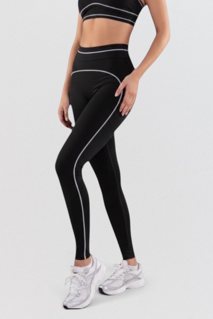 Model wearing LUPPO black high-waisted leggings with white contrast contour piping and matching sports bra