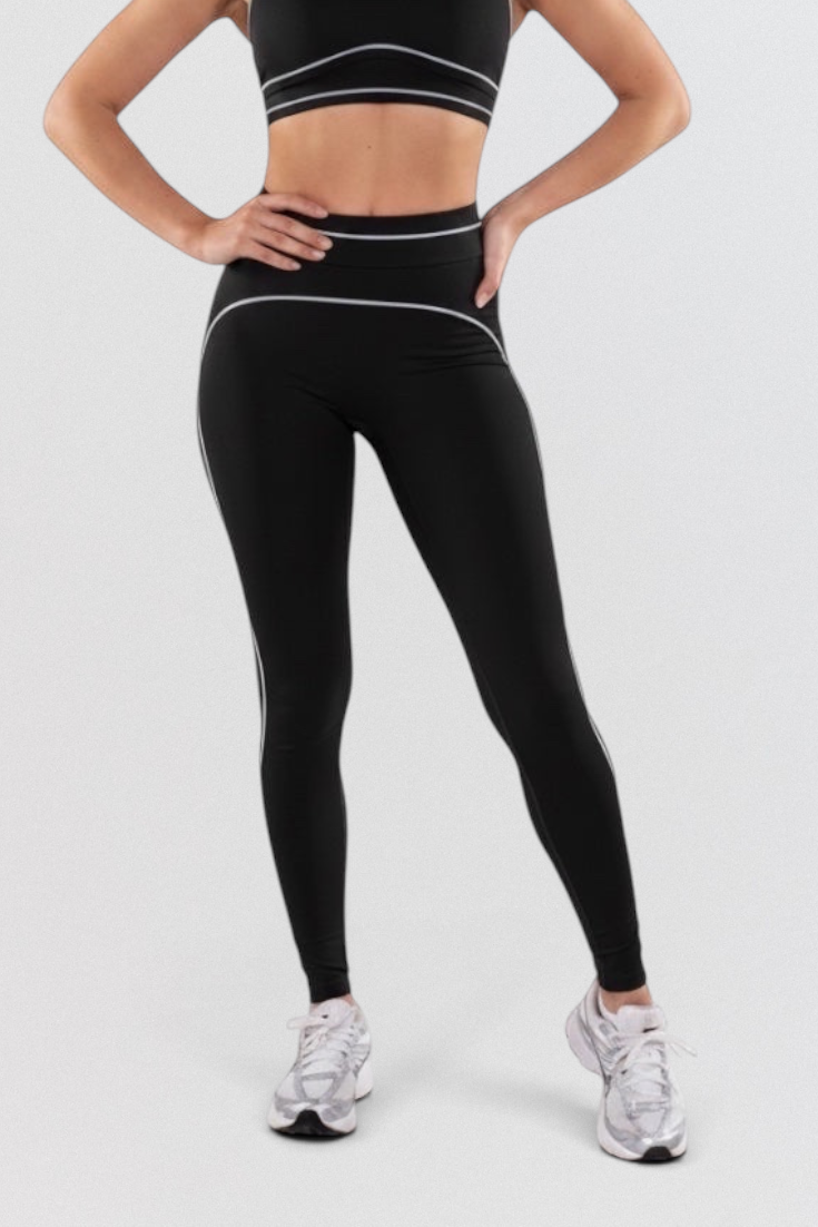 LUPPO model wearing black high-waisted leggings and matching sports bra with white contrast contour piping